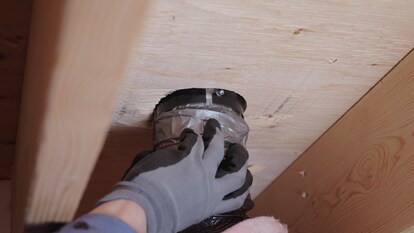 Underneath view of a contractor using the included removable duct collar to hook the vent up to ducts